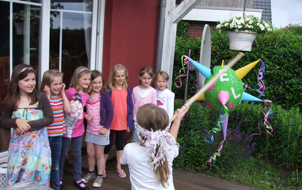 die Geburtstagsgäste zerschlagen die Pinata