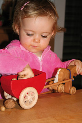Kind spielt mit Holzpferd und Wagen