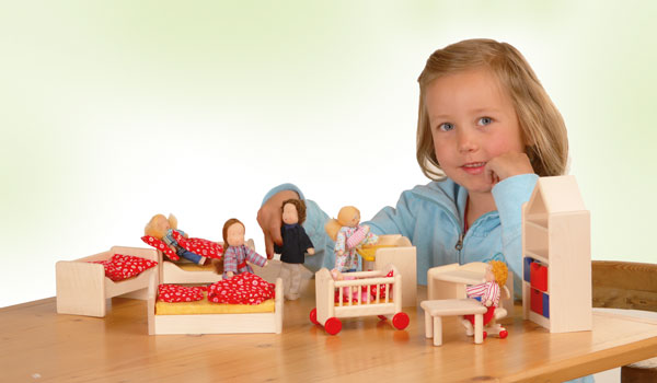 Mädchen spielt mit Puppenhausmöbeln