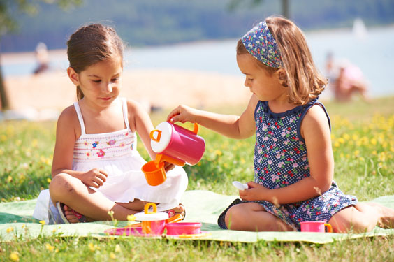 zwei Mädchen machen Picknick im grünen mit dem Spielstabil Kaffeeservice